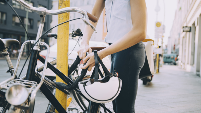 En kvinna låser fast sin cykel vid en gatustolpe på en stadsgata.