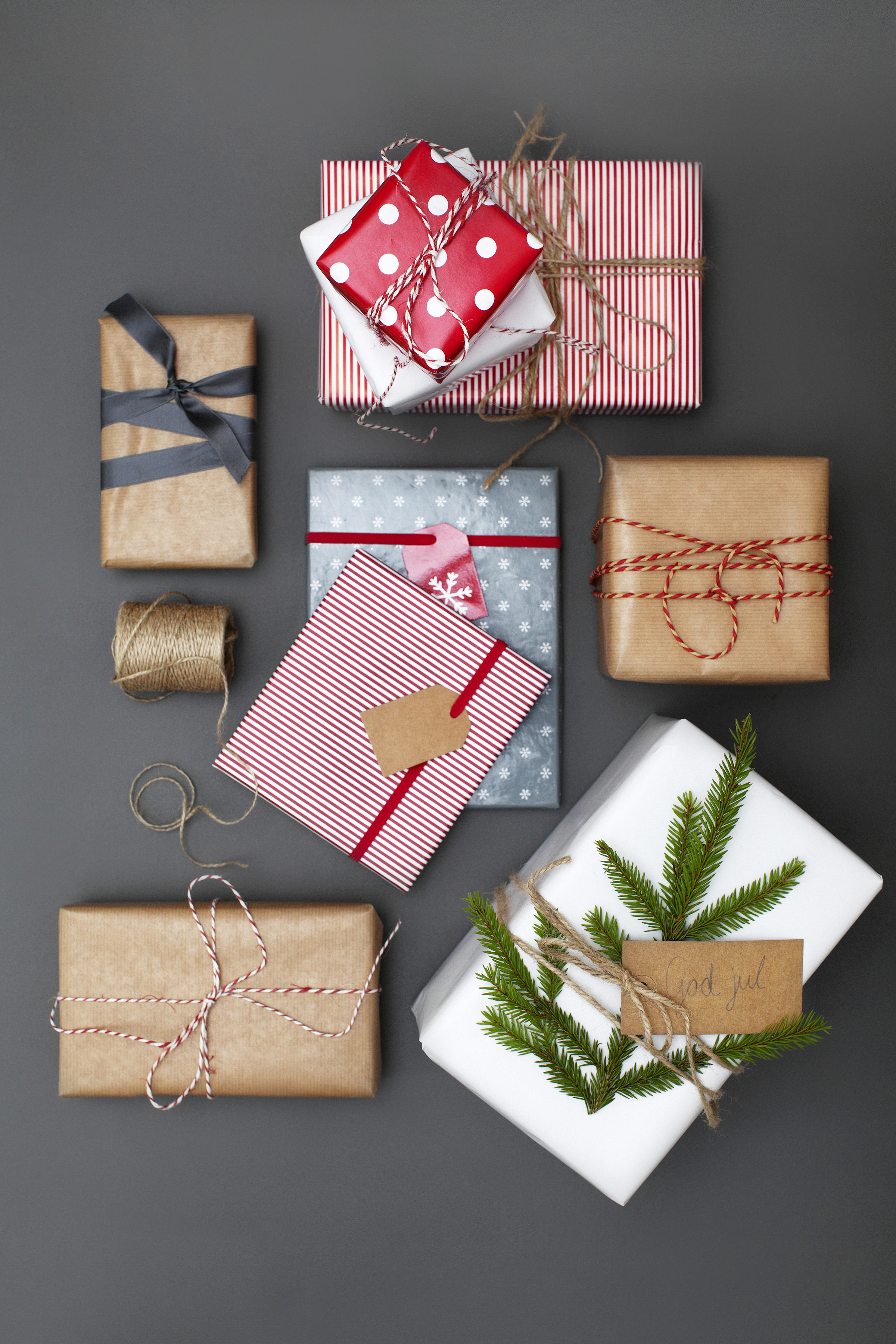Julklappar i neutrala papper men dekorerade med fina band, snören och grankvistar. 