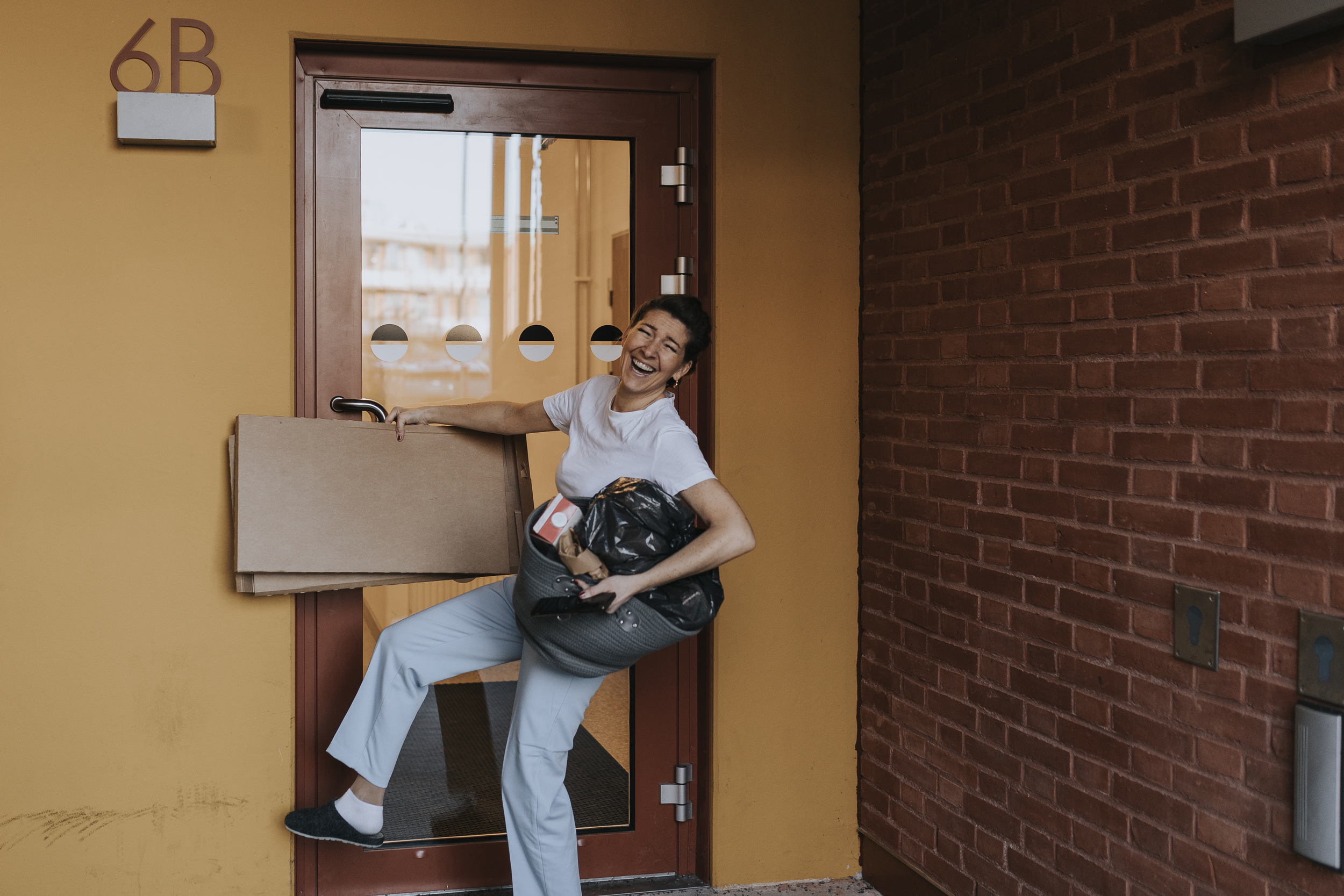 Glad kvinna på väg ut för att slänga kartonger och annat avfall i miljörummet